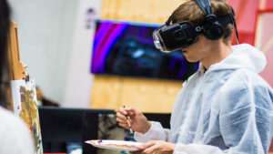 Artist Using VR For Student Education, painting picture on easel with VR headset on