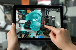 Hands holding an i-pad, augmented reality graphic appearing over an engine on the i-pad