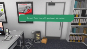 VR fire safety training scene with an office that has messy cables behind an electric heater on floor, a cardboard box in front of the heater with the text "Correct! That's 3 out of 5, you have 2 left to find"