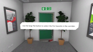 VR fire safety training scene, corridor with fire exit door held open by a fire extinguisher and a panel with the text "Use the large flat button to select fire hazards in the corridor."