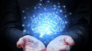 front view of two hands holding a graphic of a glowing brain, floating slightly above the hands while surrounded by a net of glowing dots connected by fine lines