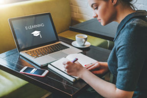 Elearning Illustration - Woman in the cafe, writing into her notebook in Front Of Laptop, with e-learning title on screen