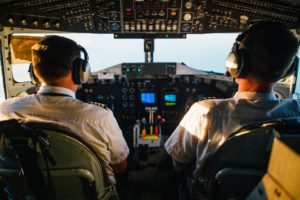 rear shot of two pilots in cockpit flying an airplane