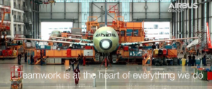 Aeroplane in aircraft hanger surrounded by luggage, includes text on-screen saying teamwork is at the heart of everything we do.
