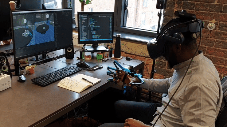 Gif of a man in an office testing a haptic engine glove and a VR headsets