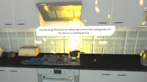 VR Fire safety training, kitchen scene, with hob and pan being on fire, with the text 'Use the large flat button to select the correct fire extinguisher to be used on a cooking oil fire.'