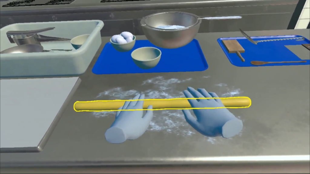 VR cooking simulation displaying blue avatar hands rolling dough on a floured surface, with kitchen utensils and ingredients arranged on blue trays.