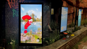 Row of interactive water safety touchscreen stations for water safety inside a canal-themed immersive environment. First screen with a cartoon character in the shape of a question mark