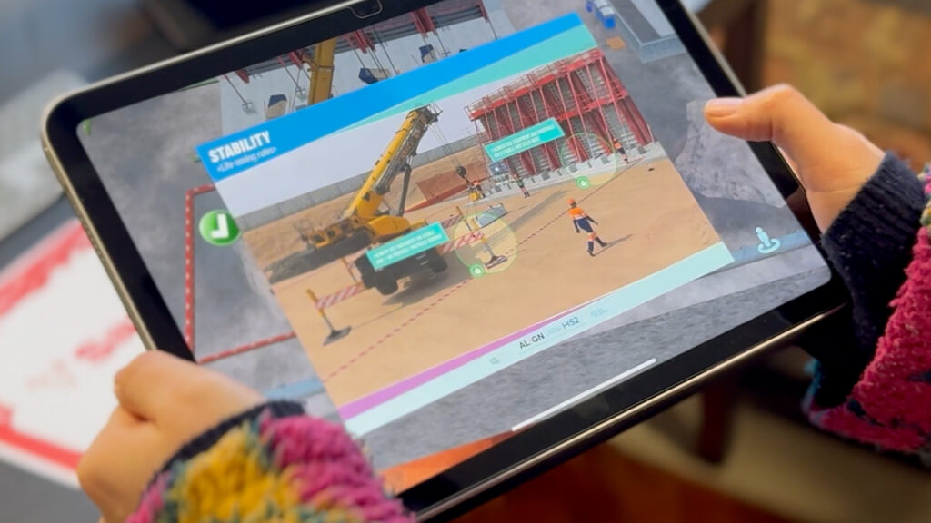 iPad showing augmented reality hazard awareness training in construction, highlighting crane stability risks and on-site safety scenarios